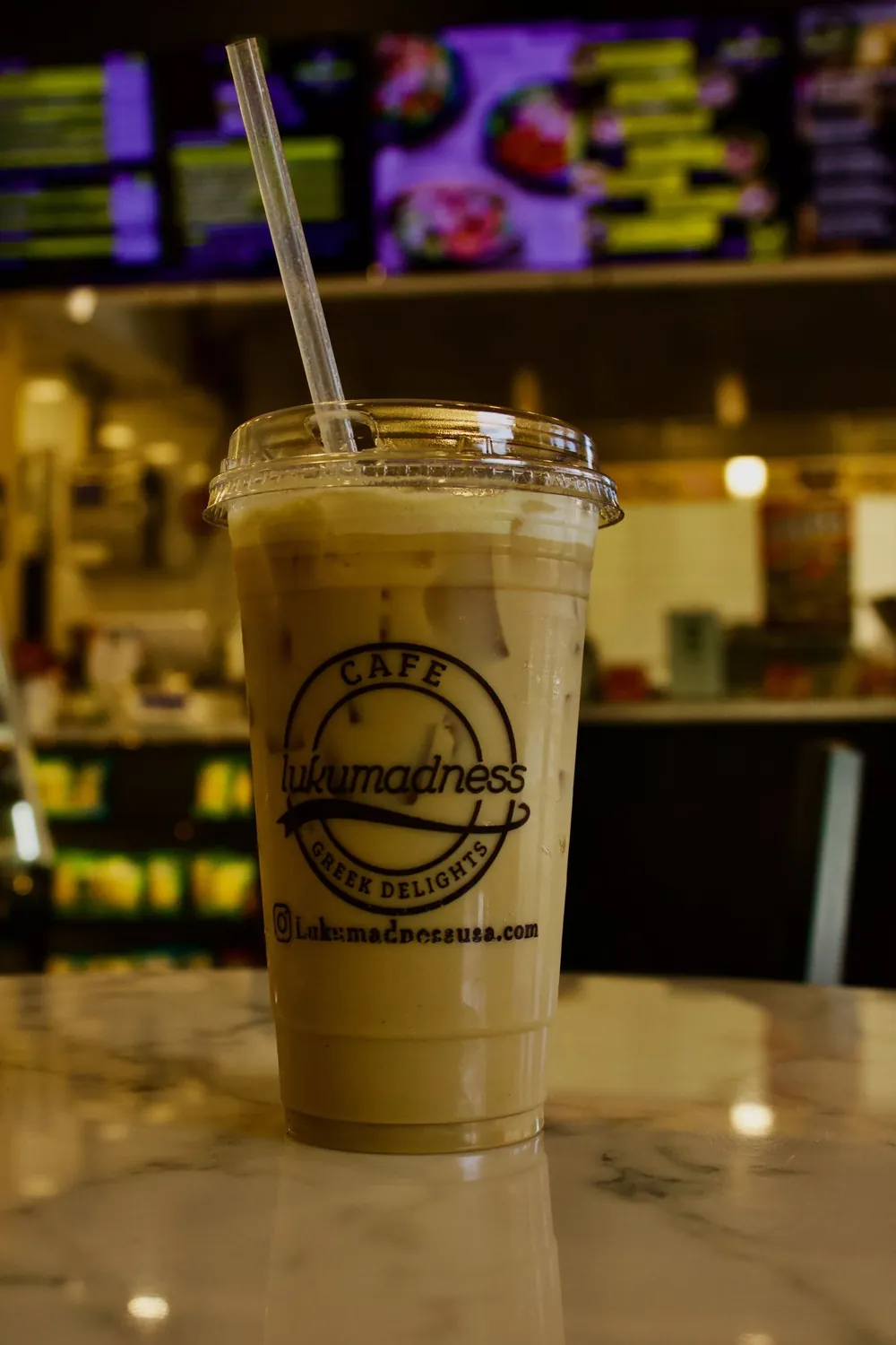 An iced latte in a LukuMadness cup on the café counter