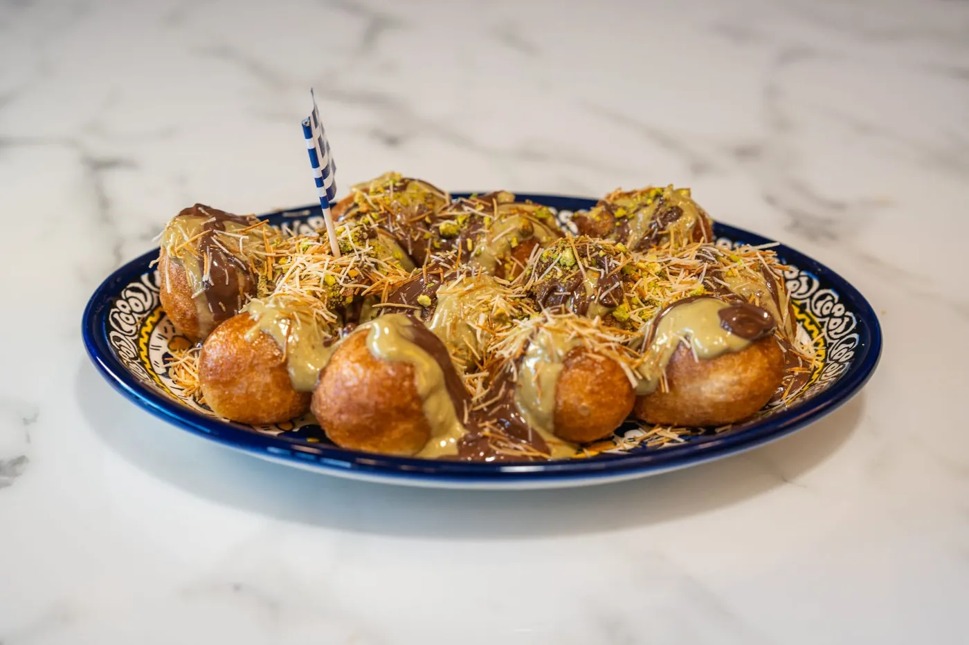 Dubai chocolate lukumades with pistachio and kataifi on a hand-painted Greek plate